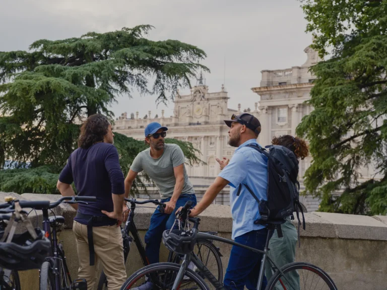 Hidden Madrid bike tour 4 Cyclists chat in the gardens by the Royal Palace of Madrid at sunset during the Hidden Madrid bike tour