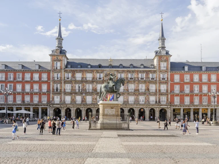 Historic Madrid Walking Tour 3 Walkers crossing Plaza Mayor in front of the Felipe III bronze statue and the Casa de la Panadería during a Dinamo Historic Madrid Walking Tour