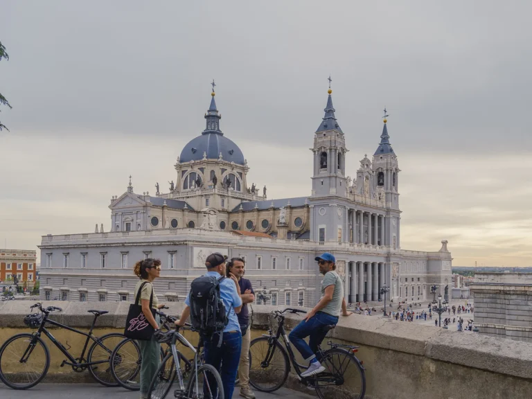 Private Madrid Bike Tour 5 Group with bikes at a viewpoint over the Almudena Cathedral at dusk on a private Madrid bike tour