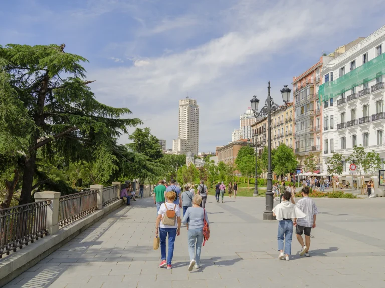 Private Madrid walking tour 5 Walkers cross the Plaza de España promenade below the Edificio España tower, private Madrid walking tour
