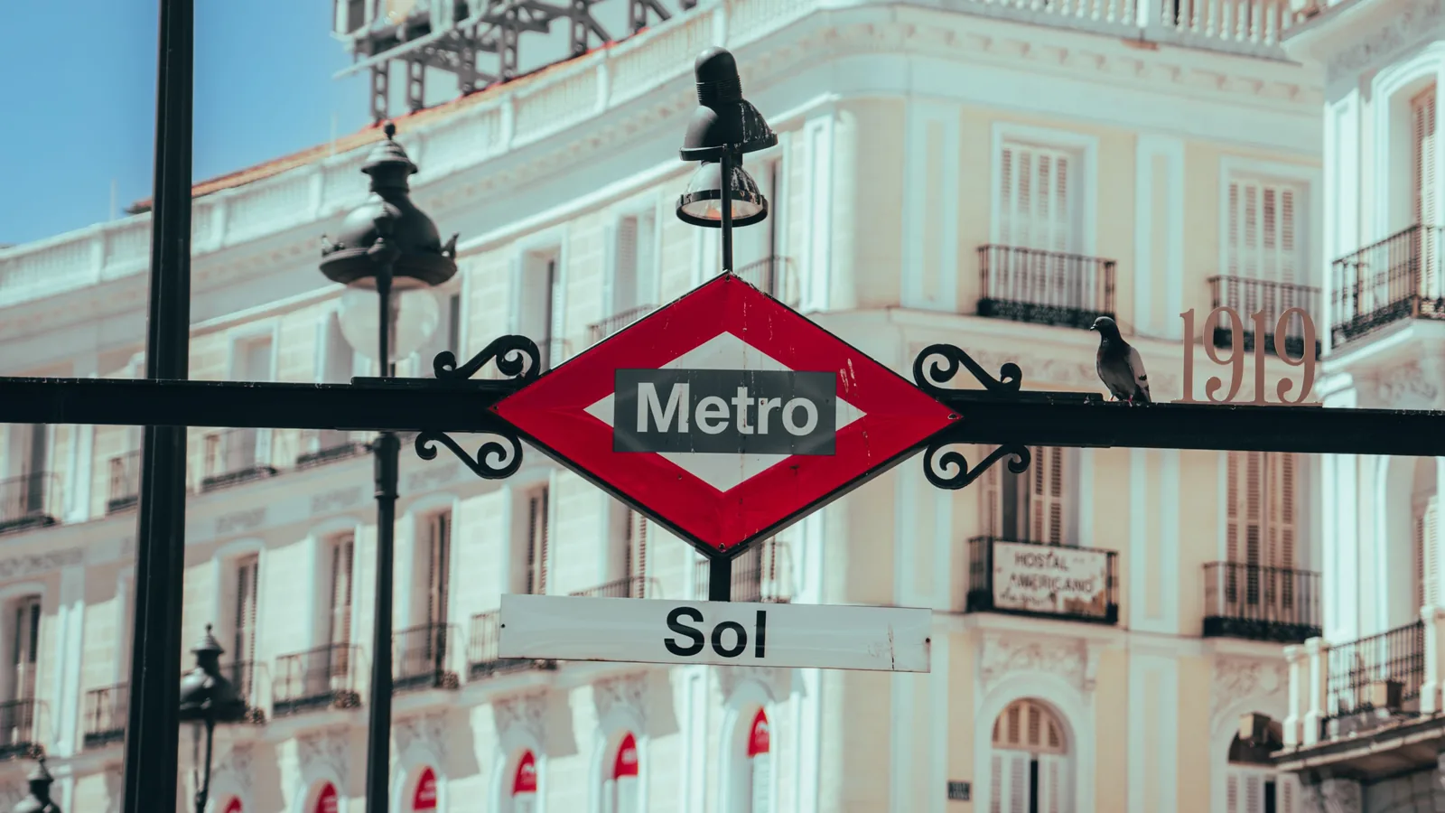 where to stay in madrid 8 Red diamond Metro sign at the Sol station entrance in Puerta del Sol, with a pigeon perched beside it