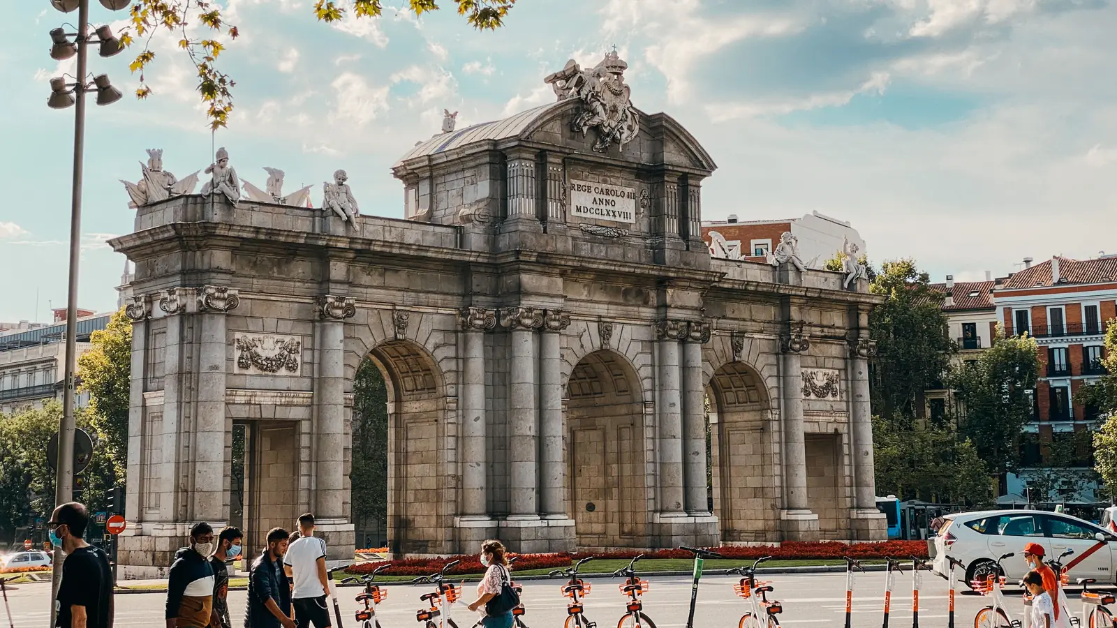 where to stay in madrid 5 Puerta de Alcalá with a row of shared bikes and pedestrians in front, at the edge of the Salamanca district