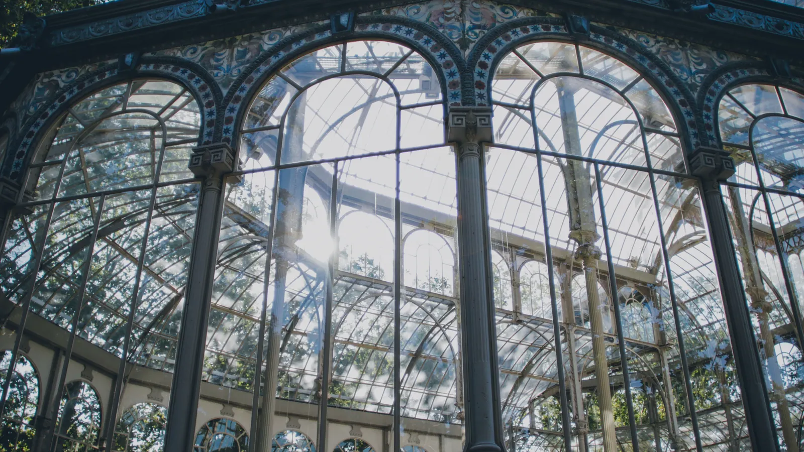 where to stay in madrid 6 Glass and iron arches of the Palacio de Cristal in Retiro Park, backlit by the sun