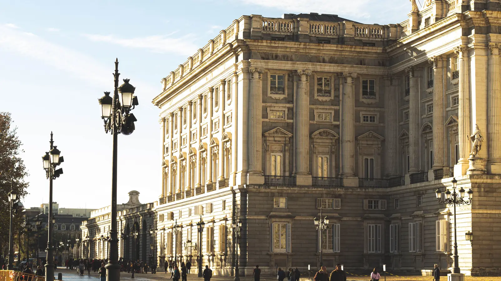 where to stay in madrid 2 Side façade of the Royal Palace of Madrid in low morning light, with people crossing the square